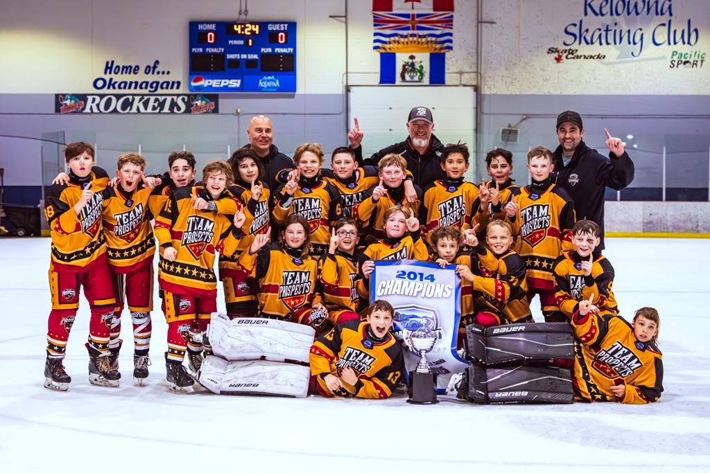 A gold and red jerseyed International Cup team poses together on the ice with their championship banner